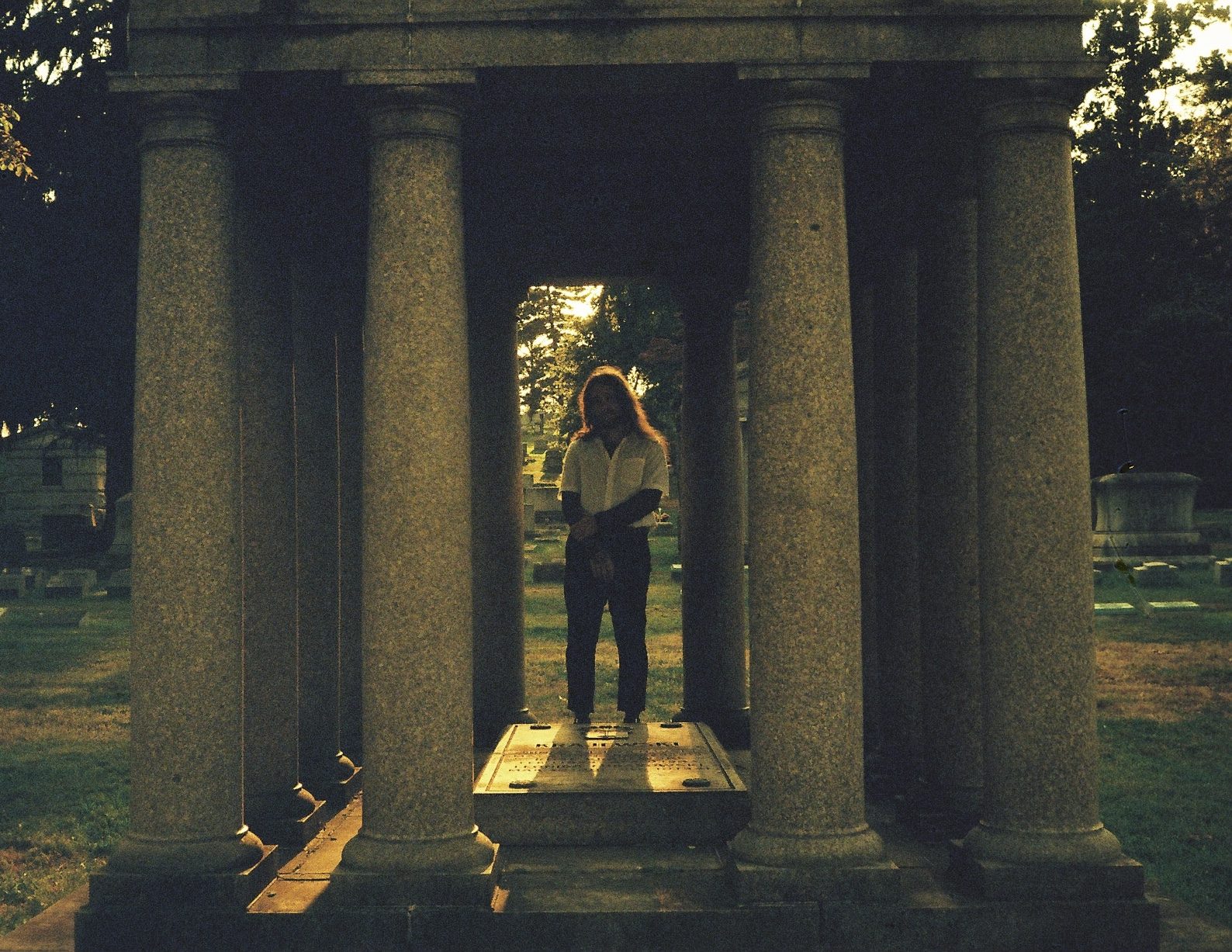 durl standing between granite columns of a mausoleum at dusk